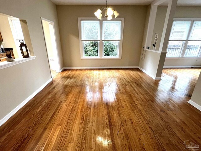 unfurnished dining area with light wood-type flooring, a wealth of natural light, and a chandelier