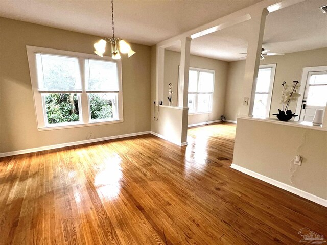 interior space with ceiling fan with notable chandelier and light hardwood / wood-style flooring