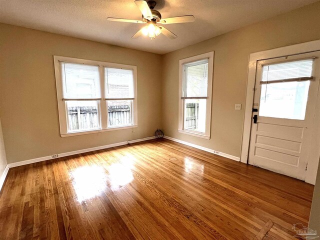 unfurnished room with a healthy amount of sunlight, ceiling fan, light hardwood / wood-style floors, and a textured ceiling