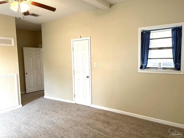 unfurnished bedroom featuring carpet, a textured ceiling, ceiling fan, and beamed ceiling