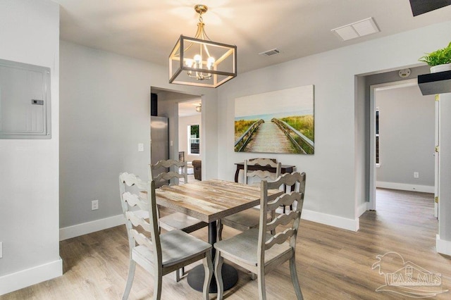 206 N G St, Pensacola, FL 32502 - dining space featuring electric panel, a chandelier, light wood-style flooring, and baseboards