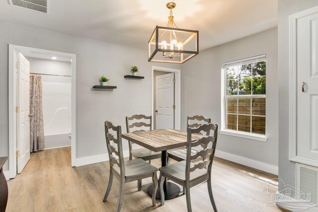 206 N G St, Pensacola, FL 32502 - dining area with baseboards, light wood finished floors, and a chandelier