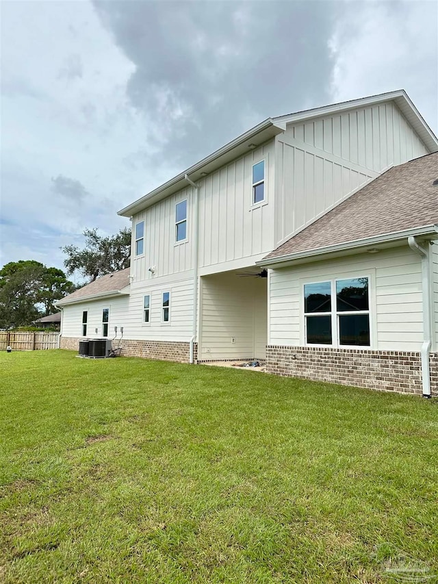 back of house with a yard and central air condition unit