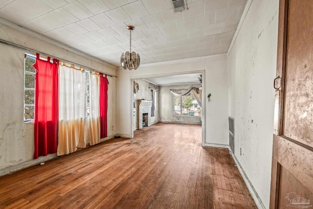 interior space with hardwood / wood-style flooring, crown molding, a brick fireplace, and an inviting chandelier