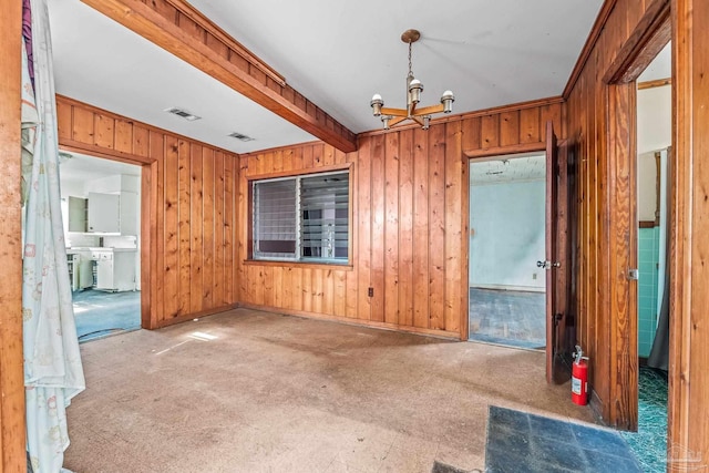 spare room featuring beam ceiling, a notable chandelier, and wooden walls