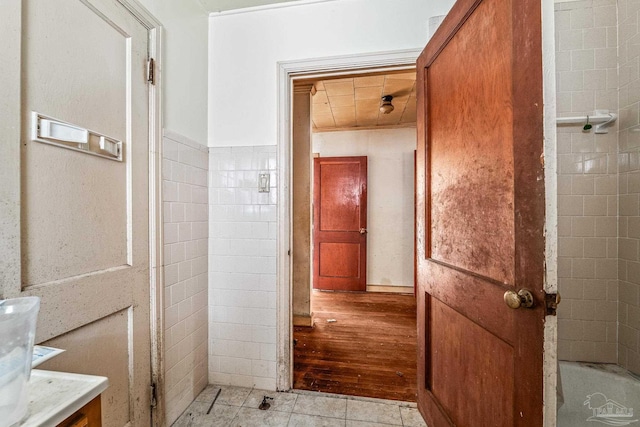 bathroom with tile patterned flooring, vanity, tile walls, and a tub to relax in