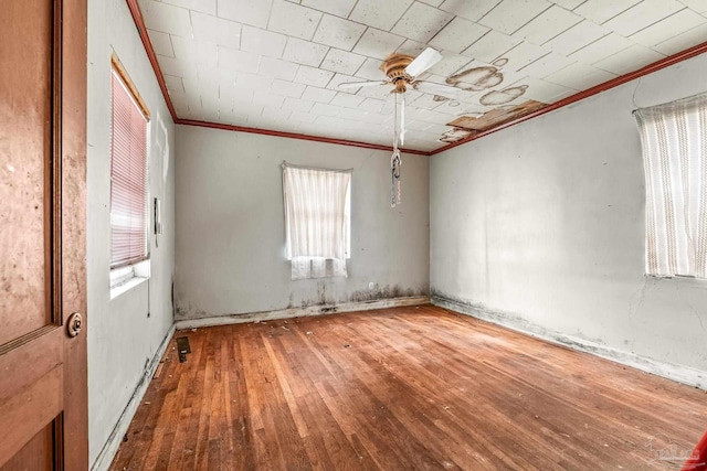 empty room featuring wood-type flooring, ornamental molding, and ceiling fan