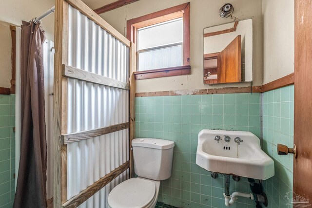 bathroom featuring tile walls, sink, a shower with curtain, and toilet