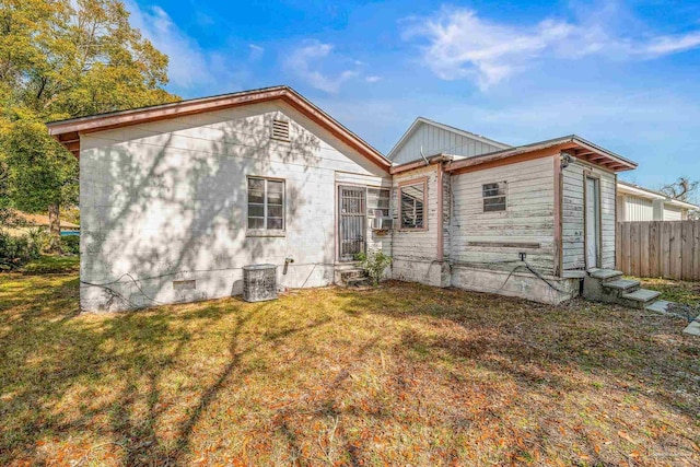 rear view of property featuring a lawn and central air condition unit