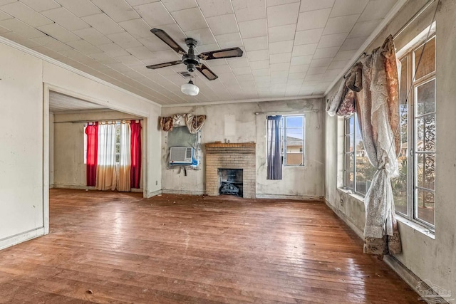 unfurnished living room with hardwood / wood-style floors, crown molding, a healthy amount of sunlight, and a brick fireplace