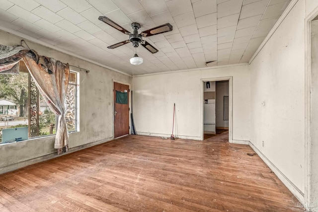 empty room featuring hardwood / wood-style flooring, ornamental molding, and ceiling fan