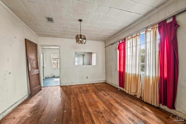 unfurnished room featuring an inviting chandelier, wood-type flooring, and ornamental molding