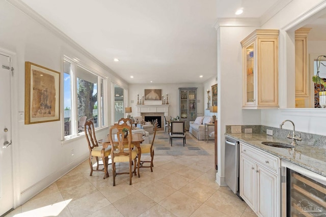 kitchen with beverage cooler, a fireplace, a sink, open floor plan, and light stone countertops