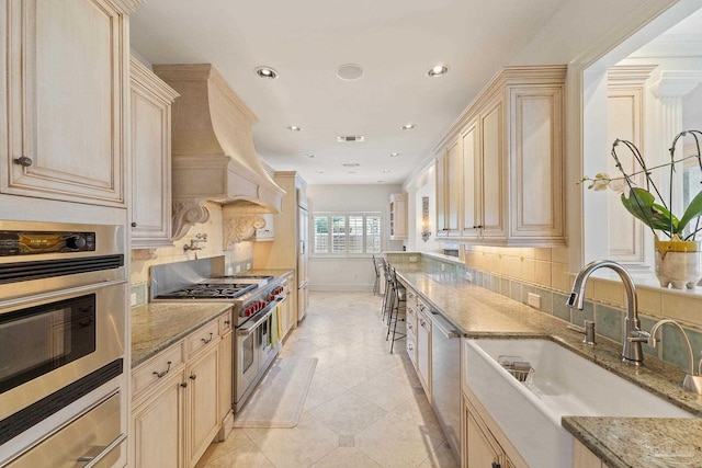 kitchen featuring light stone countertops, tasteful backsplash, appliances with stainless steel finishes, and a sink