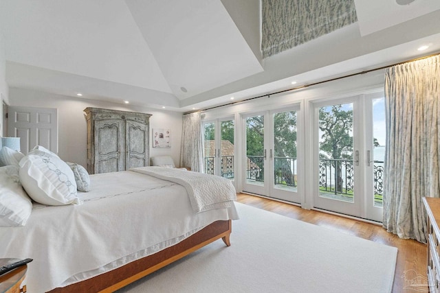 bedroom featuring multiple windows, access to exterior, light wood-type flooring, and high vaulted ceiling