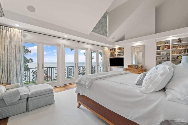 bedroom with hardwood / wood-style flooring, ensuite bathroom, and high vaulted ceiling