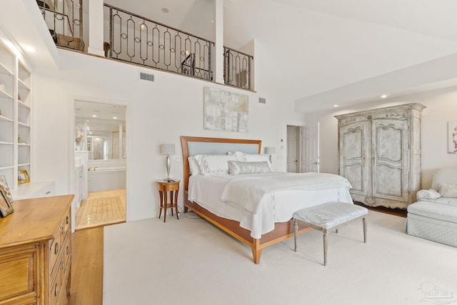 bedroom with ensuite bathroom, a towering ceiling, and visible vents