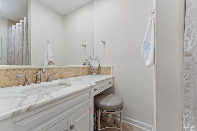 bathroom featuring baseboards, backsplash, and vanity