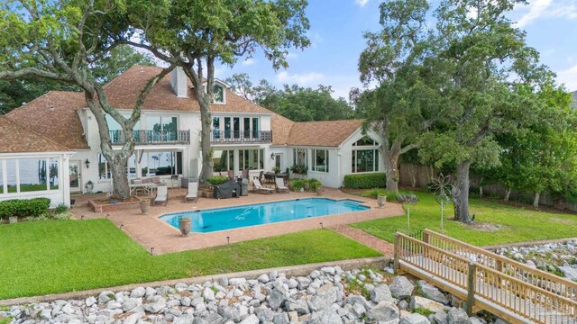 back of house with a sunroom, a water view, and a yard