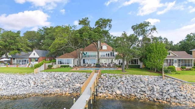 dock area featuring a water view, a lawn, fence, a balcony, and an outdoor pool