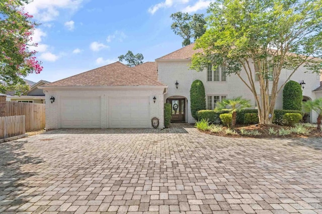 view of front of property featuring a garage, fence, decorative driveway, and brick siding