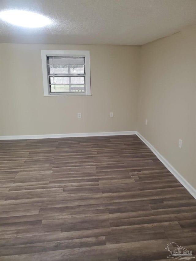 empty room with dark wood finished floors, baseboards, and a textured ceiling