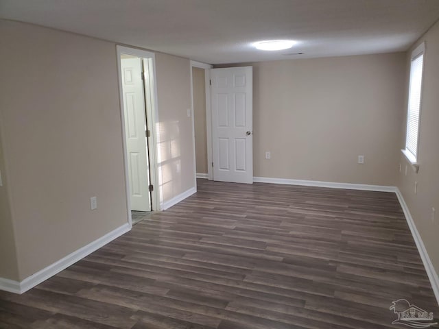 empty room featuring baseboards and dark wood-type flooring