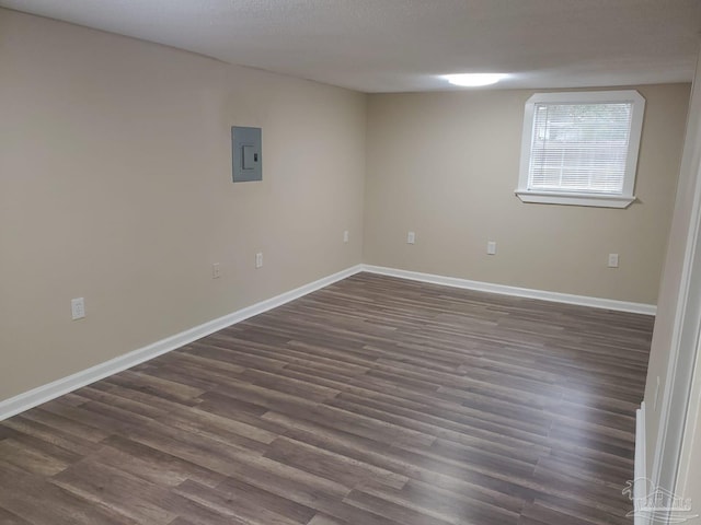 below grade area with dark wood finished floors, electric panel, and baseboards