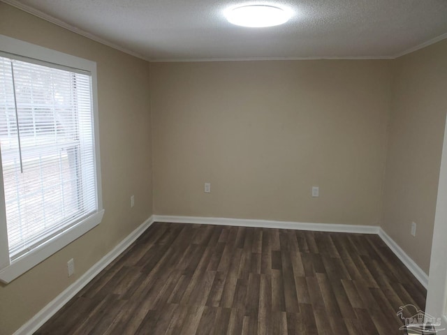 empty room with dark wood-style floors, a textured ceiling, crown molding, and baseboards