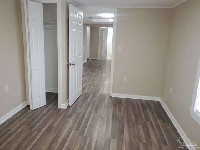 unfurnished bedroom with dark wood finished floors, a closet, baseboards, and ornamental molding