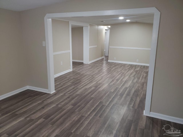 spare room featuring baseboards and dark wood-style flooring