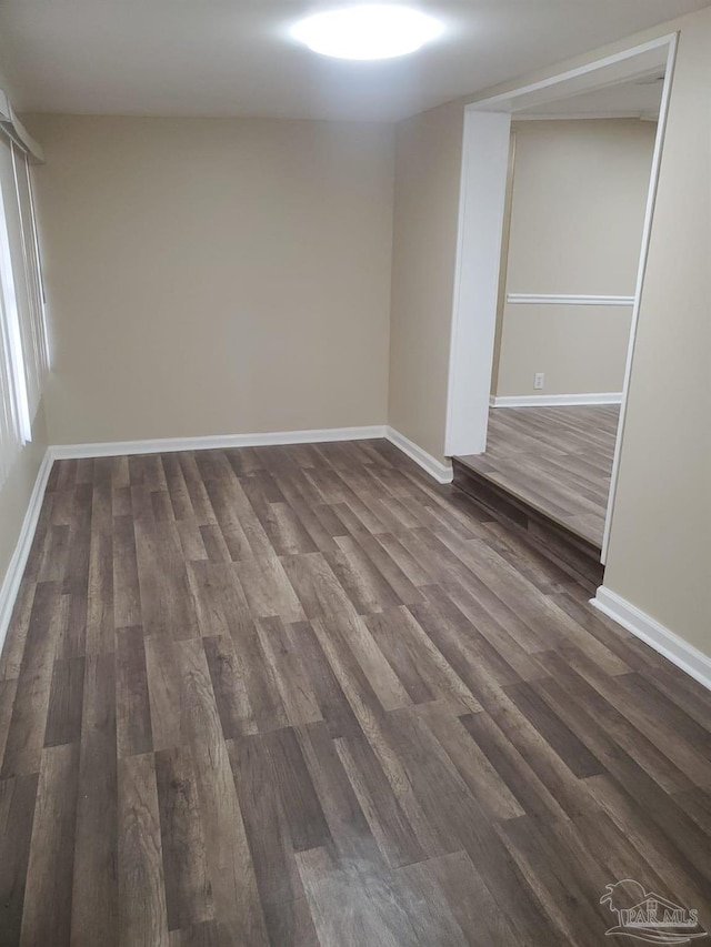 unfurnished room with baseboards and dark wood-style floors