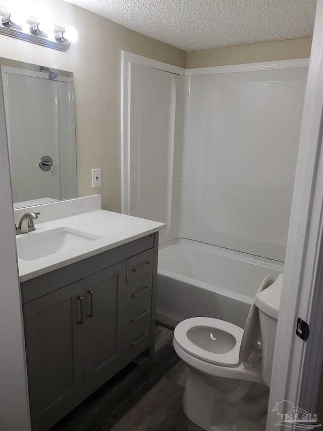 full bath featuring toilet, vanity, bathing tub / shower combination, wood finished floors, and a textured ceiling