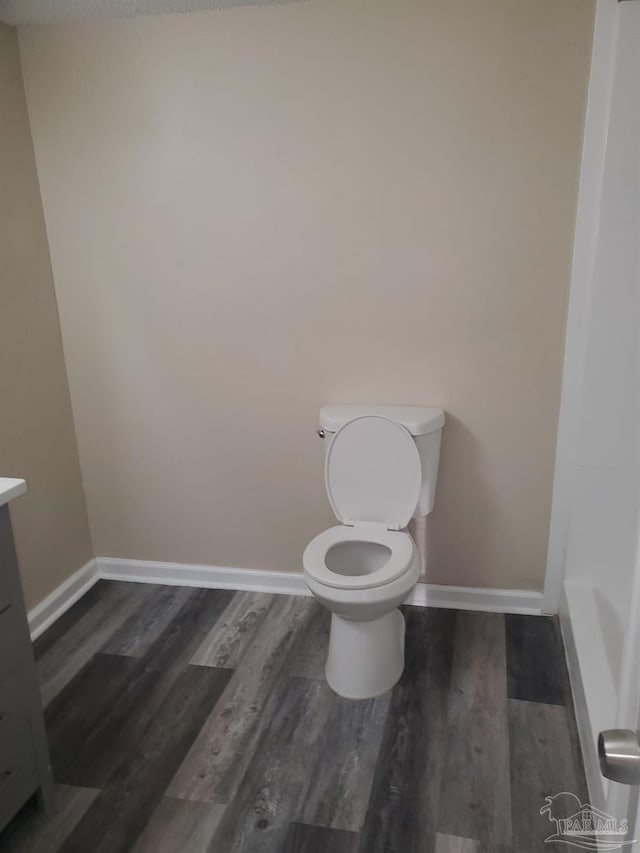 bathroom with vanity, toilet, wood finished floors, and baseboards