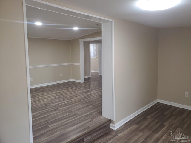 spare room with lofted ceiling, dark wood-type flooring, and baseboards