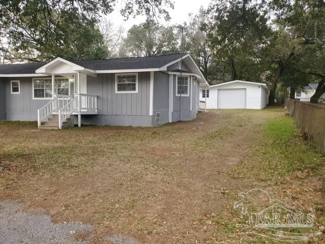 view of front of property featuring driveway, fence, an outdoor structure, a front yard, and a garage