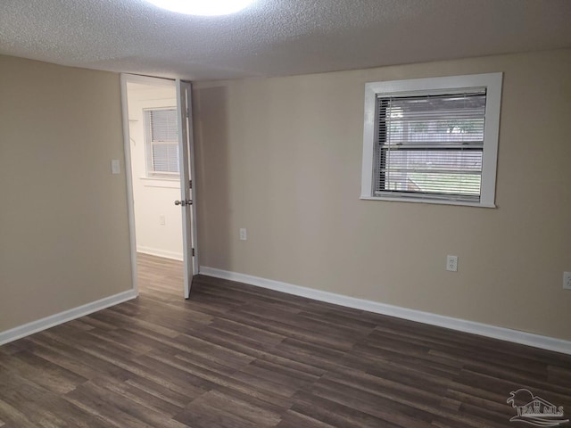 empty room featuring dark wood-style floors, baseboards, and a textured ceiling