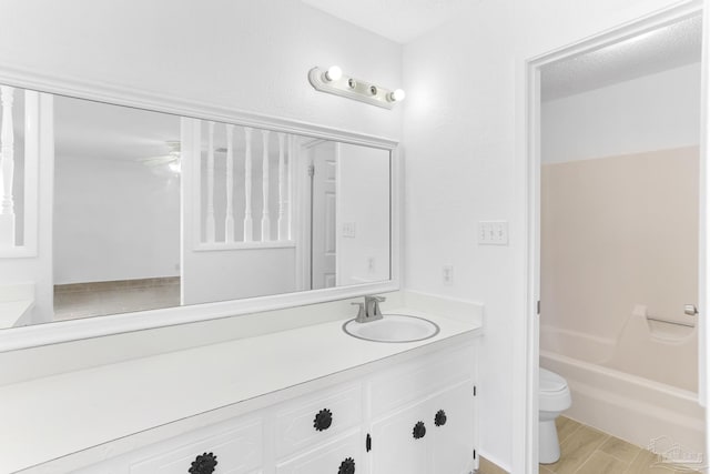 full bathroom with ceiling fan, washtub / shower combination, hardwood / wood-style floors, vanity, and toilet