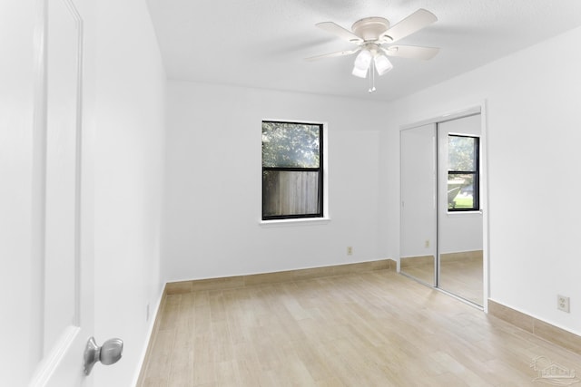 unfurnished bedroom featuring a textured ceiling, light hardwood / wood-style flooring, a closet, and ceiling fan