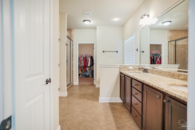 bathroom featuring a shower with door, vanity, and tile patterned floors