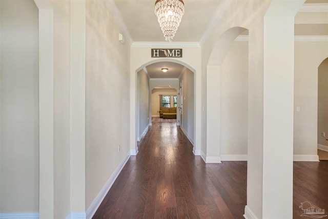 hallway with crown molding, dark wood-type flooring, and a chandelier