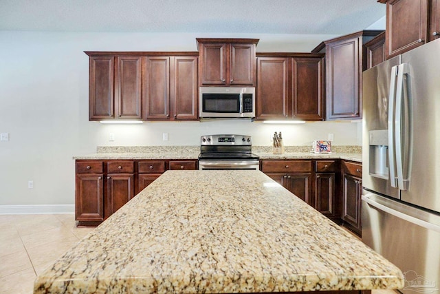 kitchen featuring light stone counters, a textured ceiling, stainless steel appliances, and light tile patterned floors