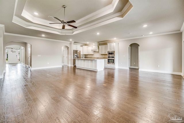 unfurnished living room with crown molding, ceiling fan, a tray ceiling, and hardwood / wood-style flooring