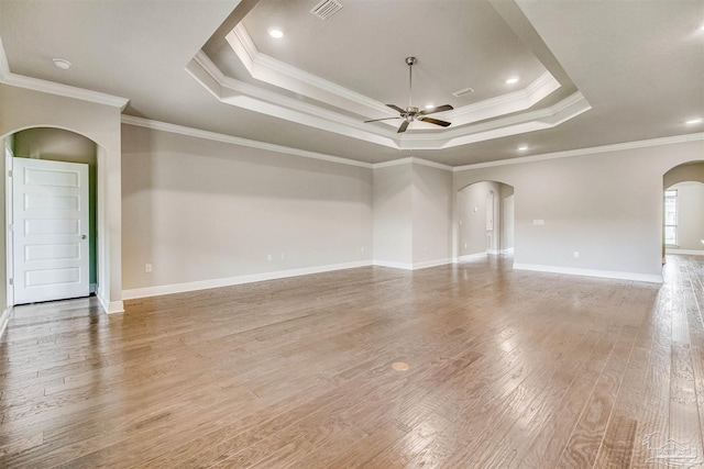 unfurnished room with a raised ceiling, crown molding, hardwood / wood-style floors, and ceiling fan