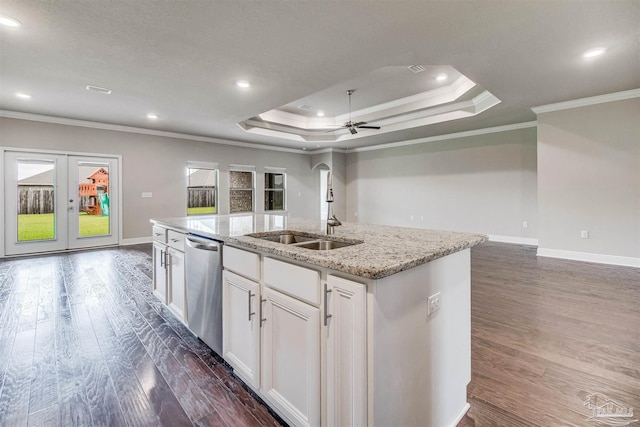 kitchen with dishwasher, white cabinetry, a tray ceiling, ornamental molding, and an island with sink