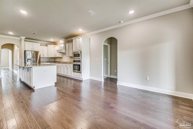 kitchen featuring an island with sink, appliances with stainless steel finishes, custom range hood, and white cabinets