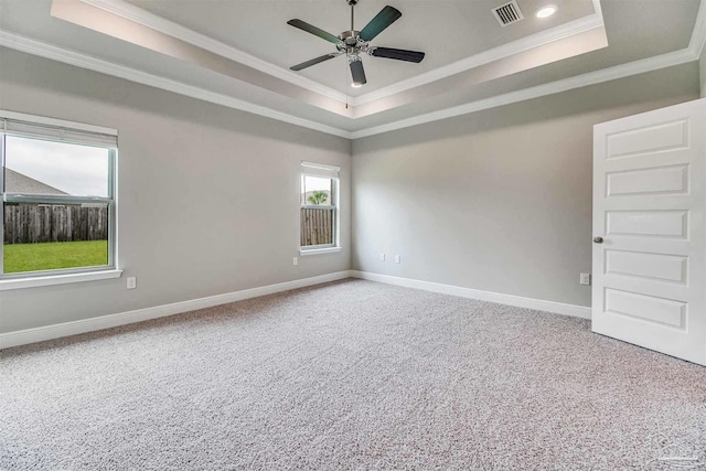 empty room with crown molding, a tray ceiling, ceiling fan, and carpet flooring