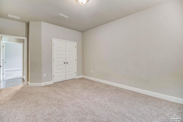 unfurnished bedroom featuring a closet, a textured ceiling, and carpet