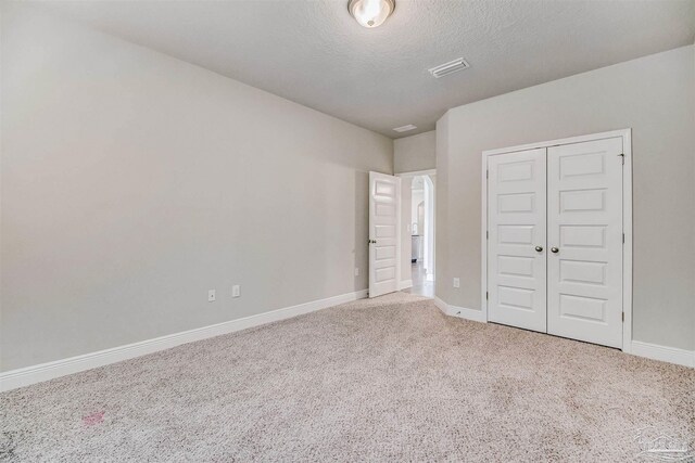 unfurnished bedroom featuring carpet floors, a textured ceiling, and a closet