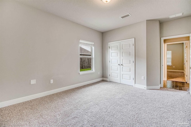 unfurnished bedroom with carpet, a closet, and a textured ceiling